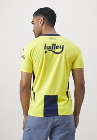 Gul sports-trøje med marineblå detaljer og sidelapper. Designet inkluderer et "halley" tryk på bagsiden og korte ærmer.