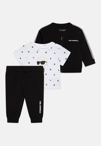 Completo per bambini composto da un giubbotto nero con zip e strisce bianche, una maglietta bianca con stampa grafica e pantaloni neri.