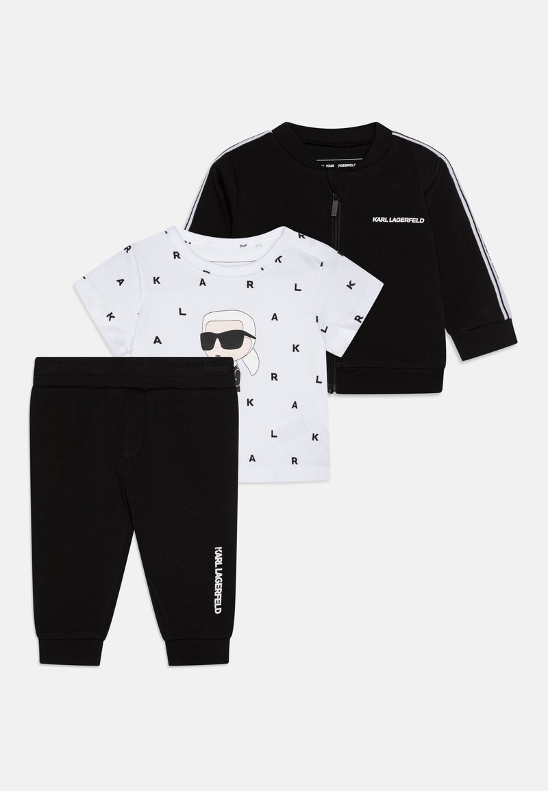 Completo per bambini composto da un giubbotto nero con zip e strisce bianche, una maglietta bianca con stampa grafica e pantaloni neri.
