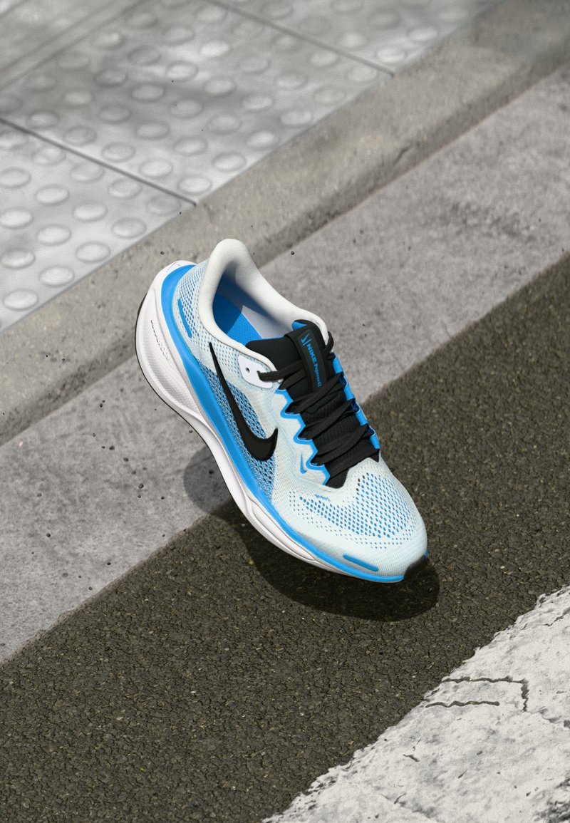 Baskets de course bleu clair avec des accents noirs, tige en mesh, lacets noirs et semelle blanche. Design texturé avec un logo sur le côté.
