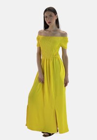 Gul off-the-shoulder maxi kjole med smocket bærestykke, korte puffede ærmer og sideslids; lavet af let, tekstureret stof.