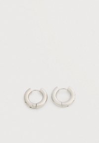 Ζευγάρι μικρών, χοντρών ασημένιων σκουλαρικιών κρίκων με λεία, γυαλιστερή επιφάνεια σε απλό λευκό φόντο.