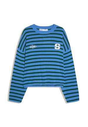 Modrá krátka košeľa s dlhým rukávom s tmavozelenými horizontálnymi pruhmi, bielym písmenom „S“ s hviezdičkami na hrudi a nášivkou „ASCEND“ na ľavej strane.