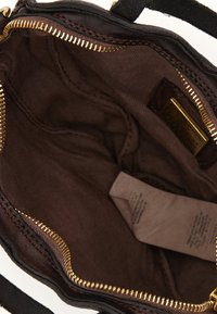 Interno di una borsa in pelle marrone con una cerniera dorata, foderato in tessuto marrone e un'etichetta. Presenta una superficie liscia e non ci sono compartimenti aggiuntivi visibili.