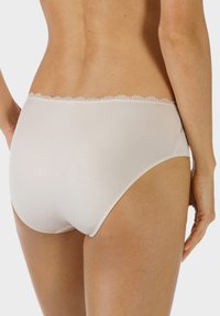 Vita bomullstrosor med en slät yta, prydda med en delikat spetskant vid midjan och en klassisk trosdesign.