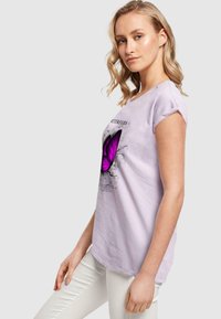 Light purple short-sleeve t-shirt featuring a large purple butterfly graphic with text above and below the design. Soft cotton fabric.