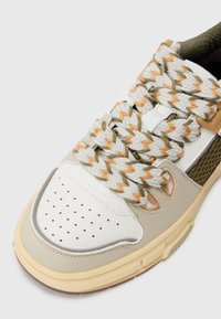 Sneaker with a white leather toe cap, tan and olive accents, textured mesh sides, and unique braided laces in white, orange, and olive.