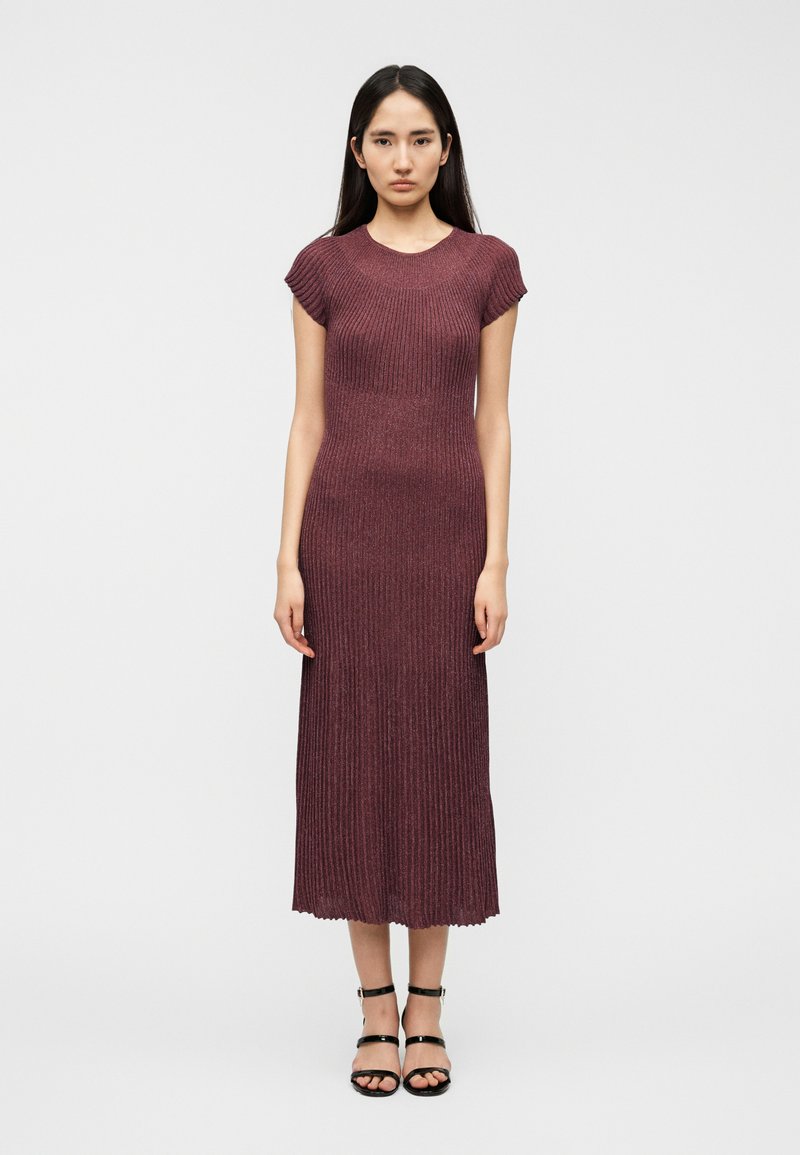 Μακρυμάνικο, ριμπ πλεκτό φόρεμα μπορντό με κοντά μανίκια, εφαρμοστή σιλουέτα και τελείωμα μέχρι τον αστράγαλο. Διαθέτει υφασμάτινη υφή και κυματιστή άκρη.