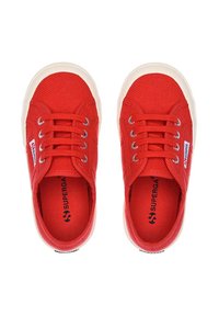 Sneakers in tela rossa con superficie texturizzata, punta rotonda, suola in gomma bianca e occhielli in metallo per i lacci. Logo del marchio visibile sul lato.