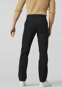 Pantalon noir à la coupe slim, en tissu doux. Il dispose de deux poches arrière avec des fermetures à bouton et d'une coupe droite.