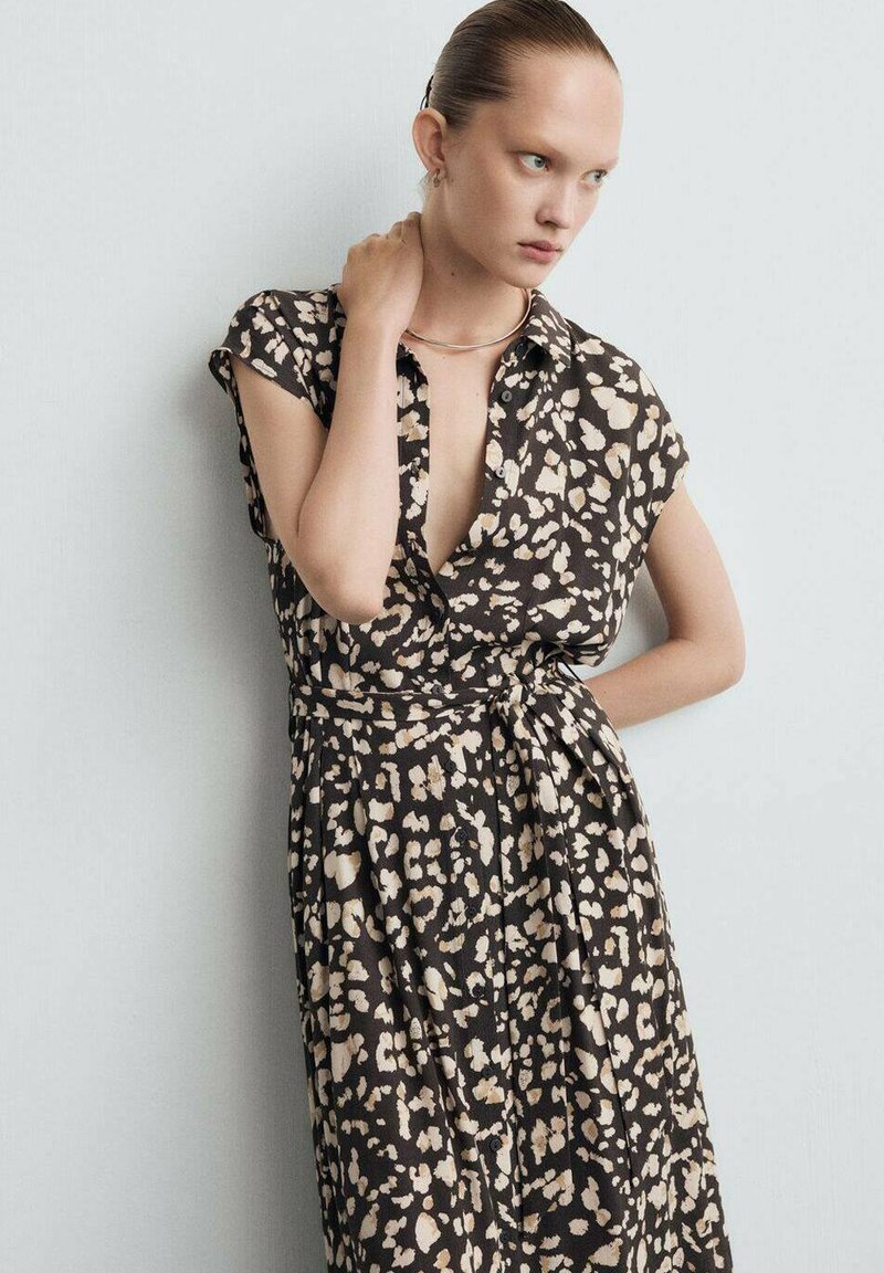Bruin- en crèmekleurige jurk met luipaardprint, korte mouwen, ceintuur in de taille en een knoopsluiting aan de voorkant. Licht, vloeiend stof met een ontspannen pasvorm.