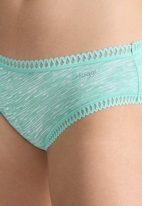 Sous-vêtements en coton vert menthe clair avec un motif rayé texturé, dotés d'une bordure en dentelle festonnée et d'un branding subtil sur le tissu.