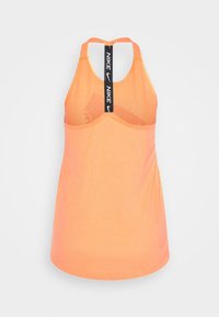 Top sportivo arancione con design a schiena scoperta. Texture liscia con una tracolla con il logo Nike e coppe integrate per il supporto.
