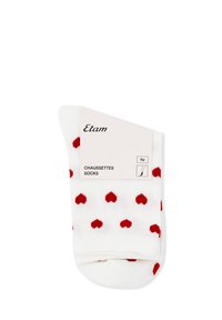 Calzini bianchi con un motivo di piccoli cuori rossi, piegati con un'etichetta bianca che mostra il nome del marchio "Etam" e i dettagli del prodotto.