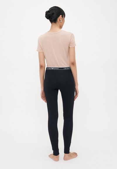 Ljusrosa figurformad T-shirt i kombination med svarta elastiska leggings med en märkesmidja. Mjuk tyg med en slät textur och minimala detaljer.