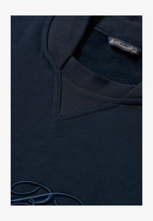 Marineblaue Poloshirt mit strukturiertem Kragen, detaillierter Naht und gesticktem Logo am Saum. Weicher Stoff mit glatter Oberfläche.