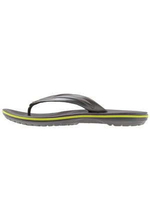 Schwarze Flip-Flops mit strukturiertem Fußbett, schlanken Gummi-Riemen und einem grünen Akzentband entlang der Sohle. Leichtes und flexibles Design.