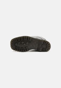 Shoe sole featuring a rugged black rubber design, with deep treads for traction and a textured surface for durability.
