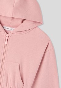 Felpa leggera rosa con chiusura a zip, cappuccio con cordino, tasca frontale e tessuto morbido al tatto. Presenta un design semplice senza ulteriori motivi.