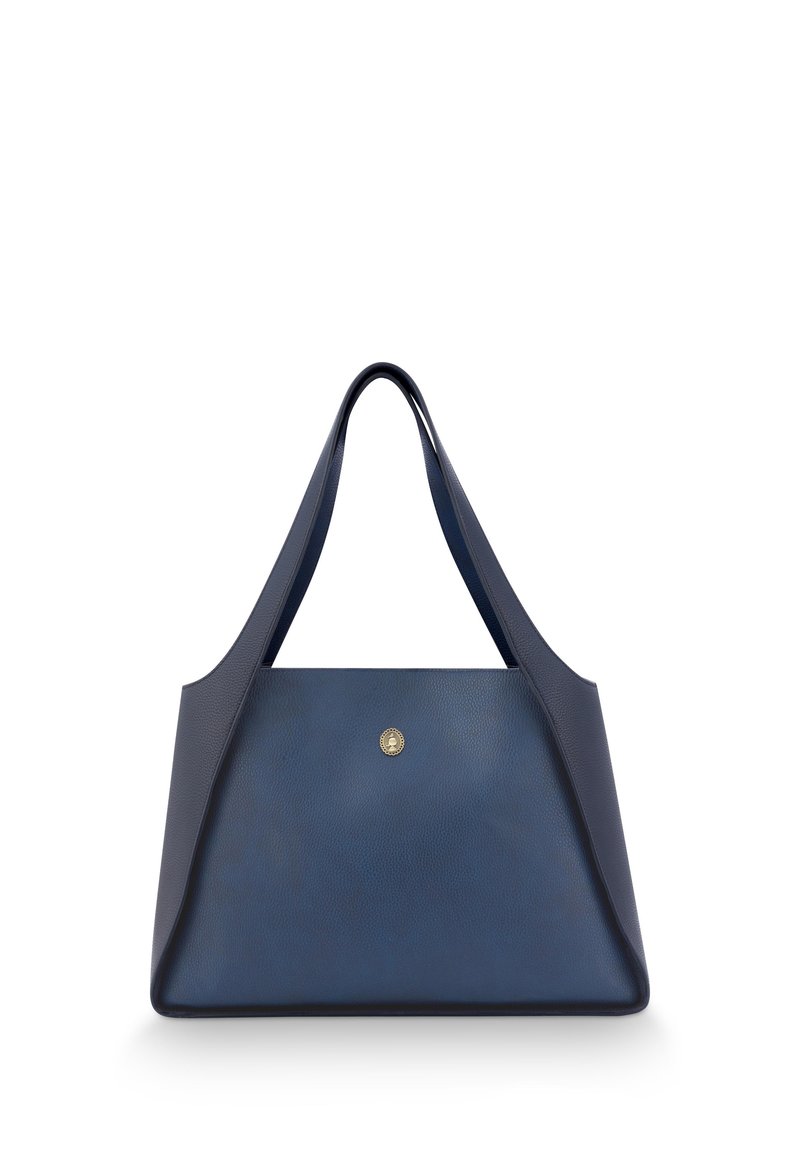 Dark blue leather tote bag with a modern design, featuring angled sides, wide straps, and a gold emblem on the front.