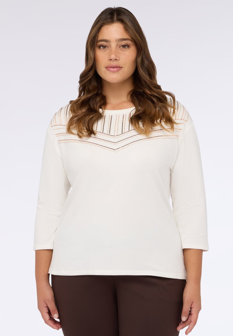 Top bianco a maniche lunghe con un motivo a chevron di sottili strisce nei toni del beige e dell'oro sul collo. Tessuto morbido e leggero.
