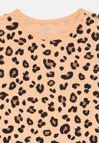 Kortärmad skjorta med leopardmönster i persikofärgad tyg, med stora svarta och bruna fläckar, rund halsringning och en mjuk textur.