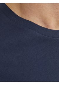 Camiseta de algodón azul marino con cuello redondo acanalado. La tela parece lisa y suave, mostrando un diseño simple y sólido.