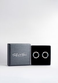 Silberfarbene, runde Ohrringe, verziert mit bunten, edelsteinähnlichen Akzenten, präsentiert in einer schwarzen, mit Samt ausgekleideten Box mit einer strukturierten Silberoberfläche.