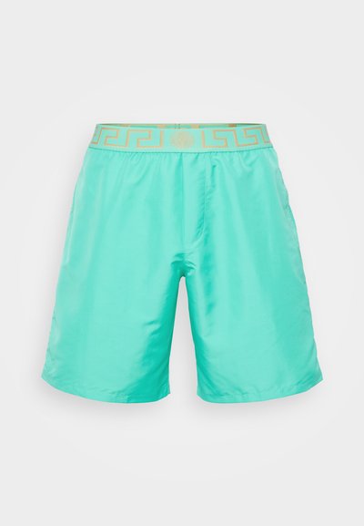 Turkosa badbyxor i lättviktig tyg; har ett midjeband med guldmönster och sidofickor. Slät yta, avslappnad passform.