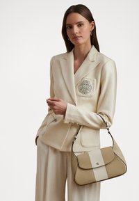 Borsa a mano in pelle beige con forma strutturata, caratterizzata da una striscia crema a contrasto e dettagli in metallo argentato. Texture liscia; tracolla removibile.