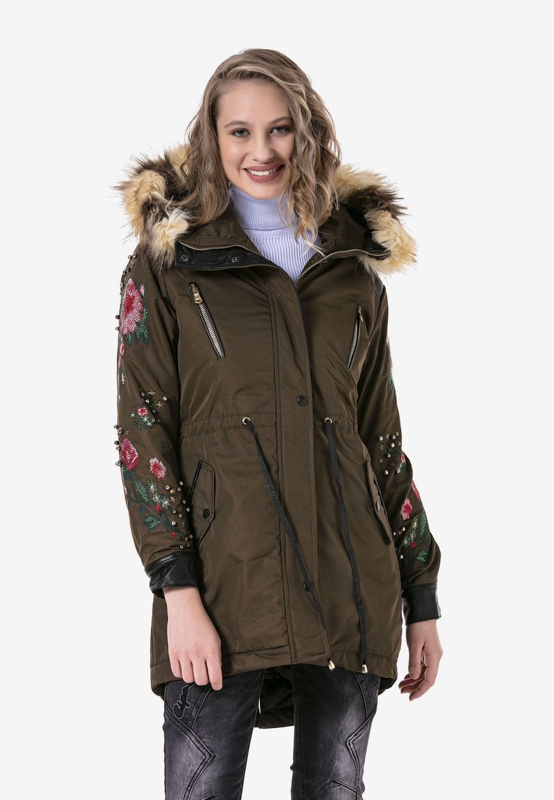 Olivgrüner Parka mit Kapuze aus Kunstfellbesatz, verziert mit floralem Stickerei und Nieten, vorderen Reißverschlusstaschen, Kordelzug in der Taille und schwarzen Akzenten.