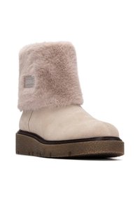 Botín de ante beige con un suave puño de piel sintética en un tono rosa pálido. Incluye una suela de goma texturizada y un sutil detalle de logo en el lateral.