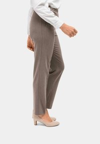 Graue maßgeschneiderte Hose mit schmal zulaufendem Bein, elastischem Bund und minimalen Nähten, kombiniert mit hellbeigen High Heels.