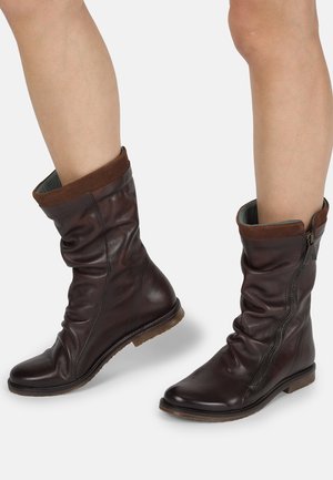 Bottines en cuir marron avec un design flou, dotées d'une fermeture éclair, d'un revers en daim et d'une semelle plate. Fini texturé et intérieur contrastant.