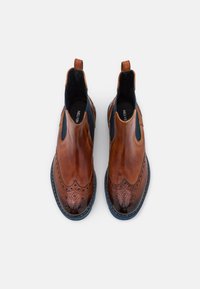 Bottines Chelsea en cuir marron avec des détails en brogue, des panneaux latéraux élastiques et une semelle texturée. Fini lisse avec des accents bleus contrastants.