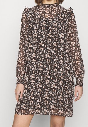 Blumenkleid aus transparenter schwarzer Stoff mit langen Ärmeln, verziert mit kleinen rosa und weißen Blumen sowie Rüschenakzenten an den Schultern.