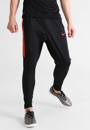 Schwarze Sporthose mit schlanker Passform, versehen mit einem roten Seitenstreifen und aus weichem, dehnbarem Material, geeignet für Sport und Bewegung.
