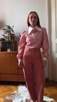 Rosa bluse med lange ermer, stor hvit krage og rosedetalj, kombinert med høytlivs rosa jeans. Teksturert stoff med avslappet passform.