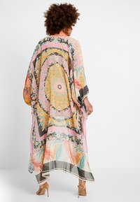 Barevný kimono s květinovými a geometrickými vzory, lehká tkanina, dlouhé rukávy a splývavý design. Okraje jsou mírně třásňové.