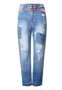 Jeans de mezclilla de color azul claro con parches desgastados y bordados. Presentan una cintura con tachuelas y dobladillos deshilachados. Ajuste clásico de pierna recta.