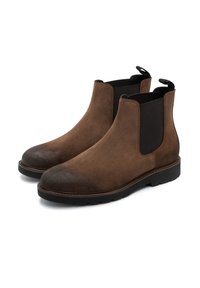 Botine Chelsea din suede maro, cu panouri laterale din elastic, vârf rotund, talpă din cauciuc negru și bucle la spate pentru a fi puse ușor.