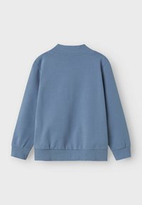 Sudadera azul claro con cuello y puños de canalé, que presenta una textura suave y un diseño casual. La parte posterior no tiene detalles adicionales.