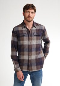 Camicia di flanella a quadri in tonalità di marrone, grigio e blu navy con colletto button-down, due tasche sul petto e maniche lunghe. Tessuto leggero.