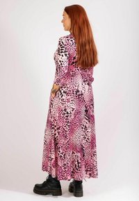 Maxiklänning med leopardmönster i rosa nyanser, långärmad, figursydd överdel, flödande kjol, tillverkad av mjukt tyg, kombinerad med grova svarta ankelskor.