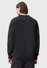 Felpa nera con collo a girocollo a coste e maniche lunghe, caratterizzata da un tessuto testurizzato e una vestibilità comoda, vista da dietro.