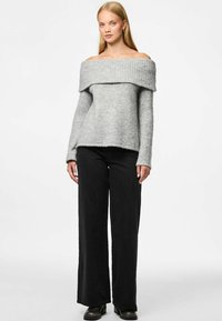 Suéter gris sin hombros con escote acanalado, mangas largas y corte relajado, combinado con pantalones anchos negros y botas de tobillo.