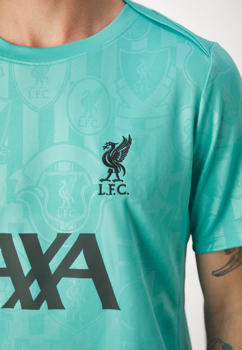 Camiseta deportiva turquesa con un patrón en relieve de los logotipos del Liverpool FC, con un escudo bordado en negro y "AXA" en letras negritas negras.