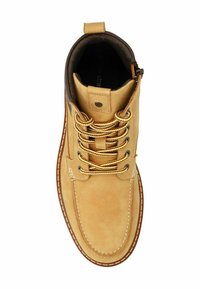 Stivale alla caviglia marrone chiaro con lacci gialli e colletto imbottito, che presenta una superficie liscia in suede e dettagli cuciti lungo la suola.