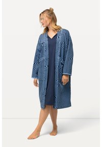 Lång marinblå kappa med vitt abstrakt vågmönster, med breda ärmar, två framfickor och en lös passform, bärs över en mörk klänning.