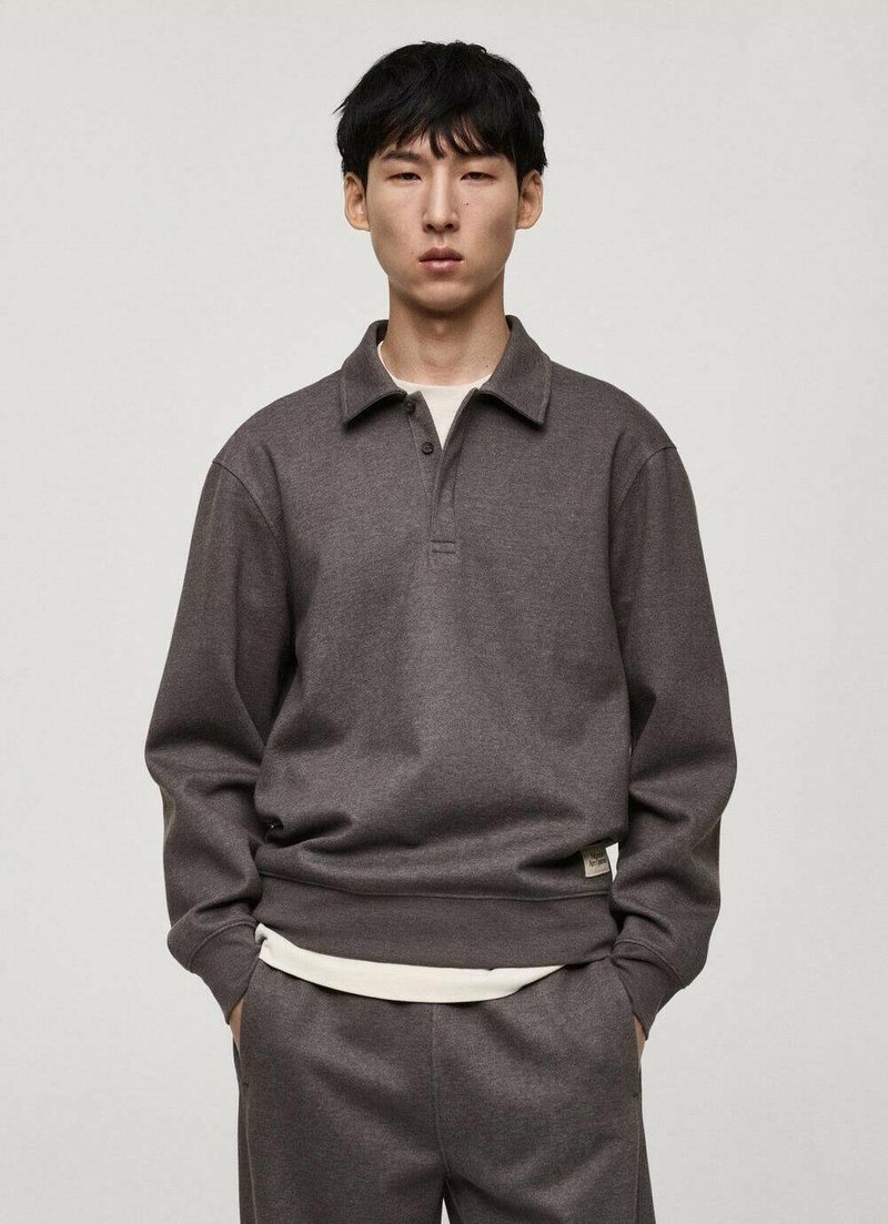 Dark gray pullover sweatshirt with a collar, three buttons, and ribbed cuffs, worn over a light-colored shirt, made from soft fabric.